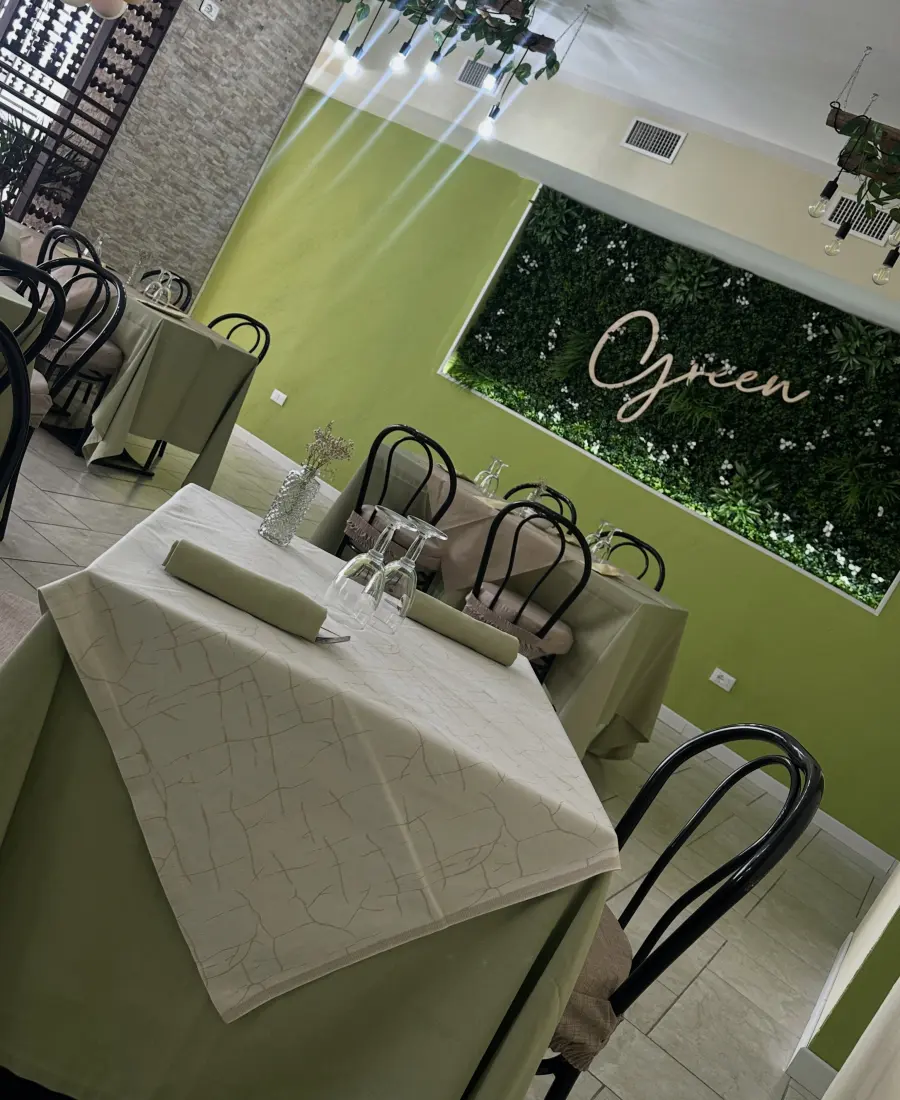 La sala del Green Restaurant, con la parete verde e i tavoli apparecchiati